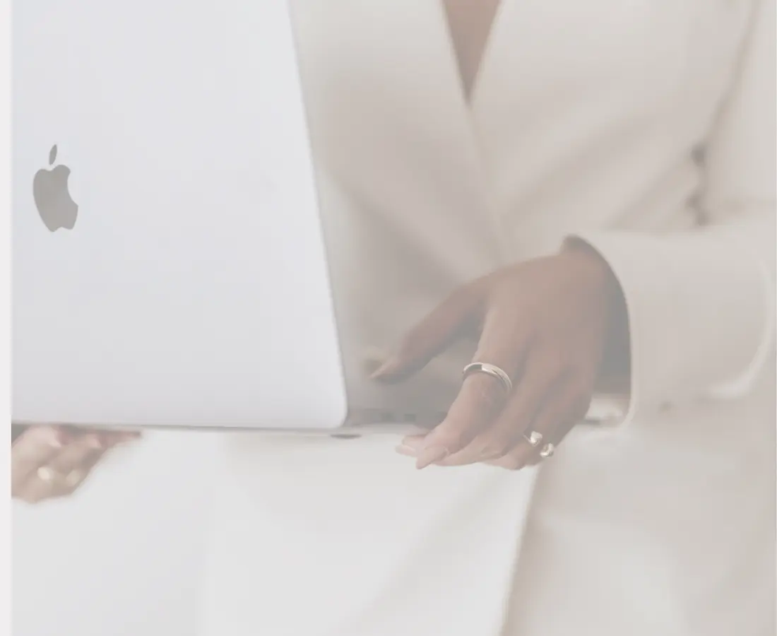 A practitioner in a white blazer holding an open laptop